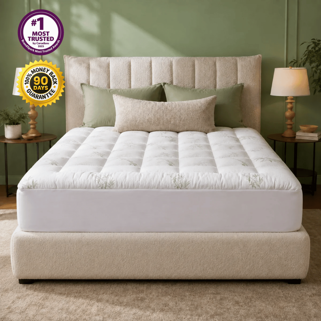 A tufted mattress on a matching upholstered bed frame in a styled bedroom. The mattress is white with a subtle light green botanical pattern, surrounded by green and beige pillows.