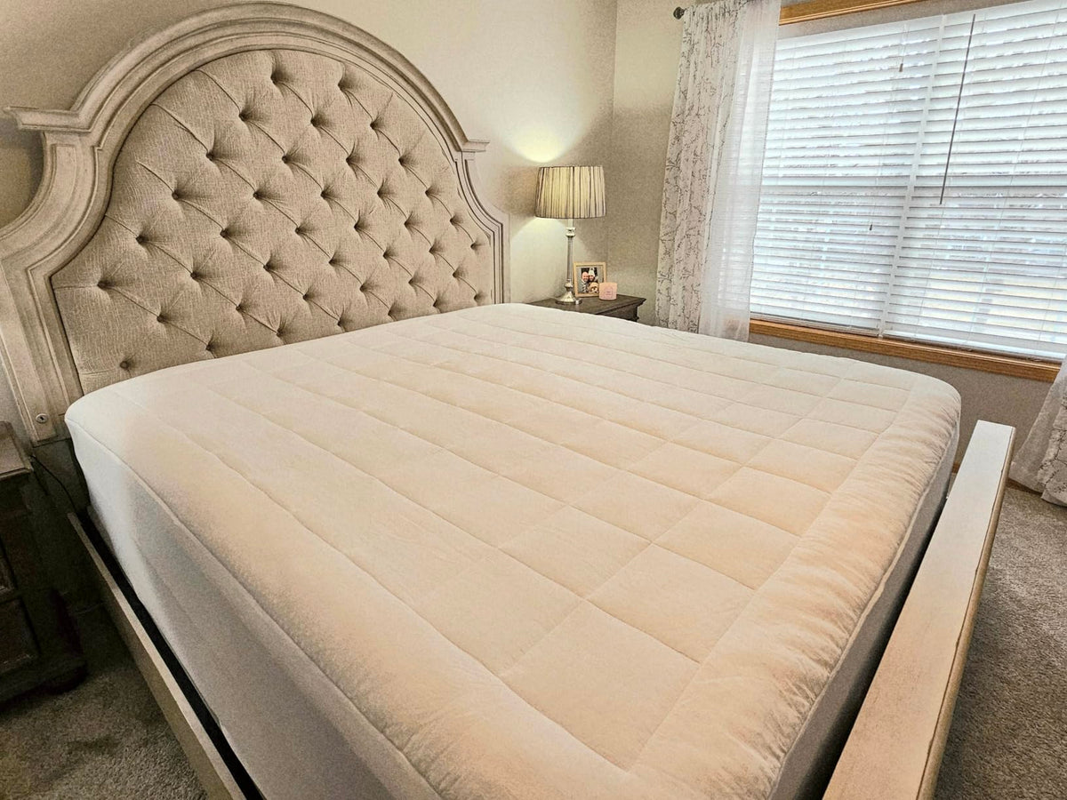 Customer's own bed made up with the Sleeplo topper in daylight, quilted squares and one fitted corner visible
